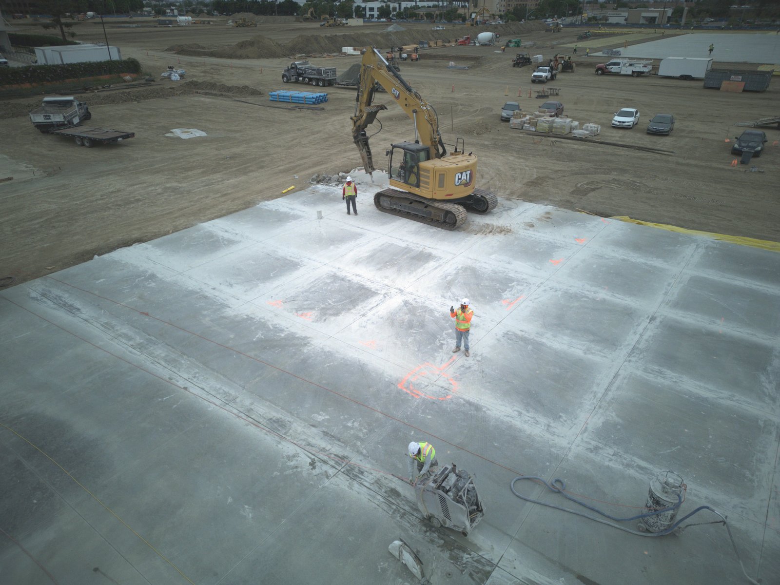 Aerial drone view of active DSI demolition site with excavator and crew clearing large concrete pad